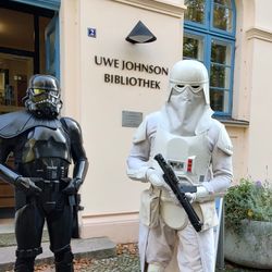 Zwei Kostümträger, als Shadow-Trooper und Snow-Trooper verkleidet, posieren vor der Tür und dem Schriftzug Uwe Johnson Bibliothek
