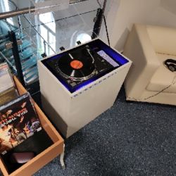 Vinylstation neben dem Trog mit den Schallplatten aus Güstrower Produktion und dem gemütlichen Sessel zum Anhören vor Ort.