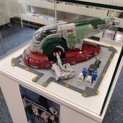 Vitrine in der Bibliothek mit einem Lego-Modell der Szene aus dem Star Wars Film Teil V, der Verschleppung von Han Solo durch den Kopfgeldjäger Boba Fett