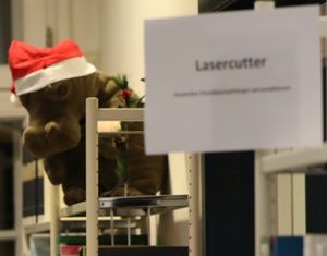 Plüschnilpferd mit Weihnachtsmannmütze und Schild mit Aufschrift Lasercutter