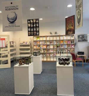Blick auf Vitrinen mit Büchern und Großplakaten mit Covergrafiken darüber hängend.
