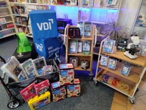 Die Neuzugänge in der Bibliothek der Dinge zusammengestellt im Eingangsbereich der Bibliothek mit Sitzwürfeln vom VDI