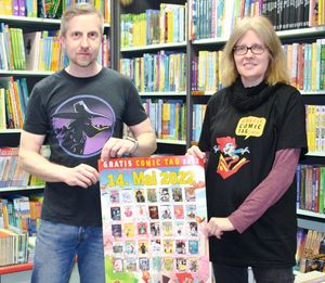 Bibliotheksmitarbeiter Marko Schönwelski und Buchladenbesitzerin Ulrike Wiechert mit Plakat und Shirt zum Gratis-Comic-Tag; (c) Frauke Naumann
