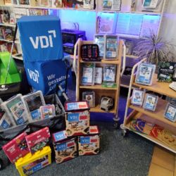 Die Neuzugänge in der Bibliothek der Dinge zusammengestellt im Eingangsbereich der Bibliothek mit Sitzwürfeln vom VDI