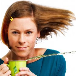 Inka Meyer, deren Haare scheinbar vom Wind verweht werden und die eine Tasse hält, aus der waagerecht Tee ausläuft; Foto (c) S. Büttner