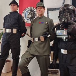 Drei Kostümträger, als imperiale Offiziere und Shadowtrooper kostümiert, stehen in der Bibliothek vor einem Banner mit dem Logo des Kostümclubs 501st German Garrison