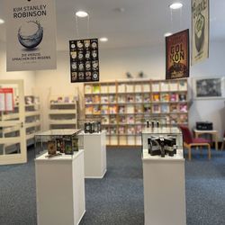 Blick auf Vitrinen mit Büchern und Großplakaten mit Covergrafiken darüber hängend.