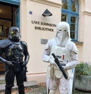 Zwei Kostümträger, als Shadow-Trooper und Snow-Trooper verkleidet, posieren vor der Tür und dem Schriftzug Uwe Johnson Bibliothek