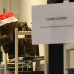 Plüschnilpferd mit Weihnachtsmannmütze und Schild mit Aufschrift Lasercutter